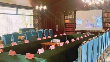 A conference room with a long table, chairs, and a projector screen.
