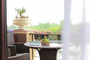 A balcony with wicker furniture, a round table, and a decorative urn with plants.