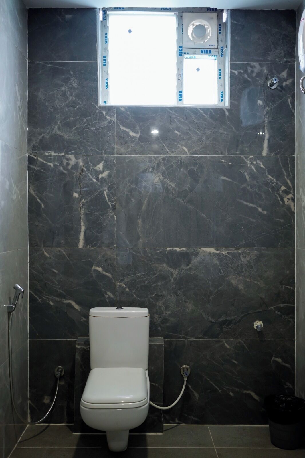 A bathroom with a toilet, a shower, and a window.