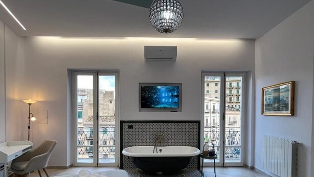 Une chambre moderne avec un grand lit, une baignoire et un téléviseur.