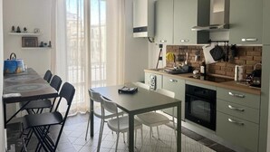 Une cuisine moderne avec un coin repas, dotée d’un mur de fond en briques, d’appareils électroménagers en acier inoxydable et de meubles de couleur claire.