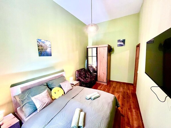 A bedroom with a bed, a chair, a wardrobe, and a TV. - Oasis Valley  (Karlovy Vary)
