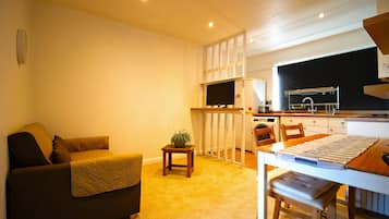A compact living space with a sofa, a small table, a kitchen area with a microwave, and a window.