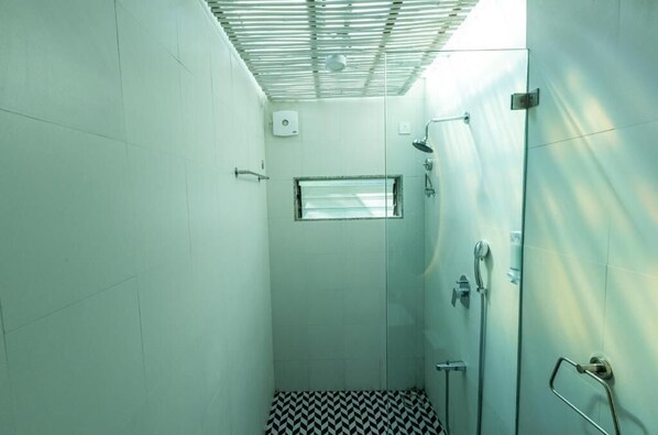A small, enclosed shower area with a glass door, a window, and a tiled floor. - Oceanature Resort Alibaug (Alibag)
