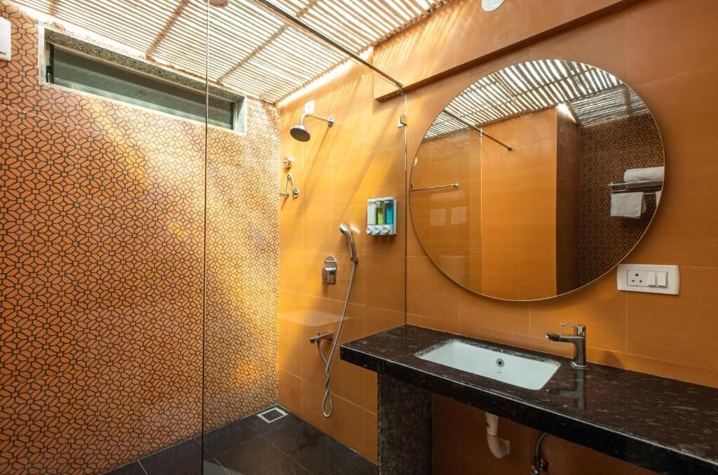 A bathroom with a patterned wall, a round mirror, a sink, and a shower.