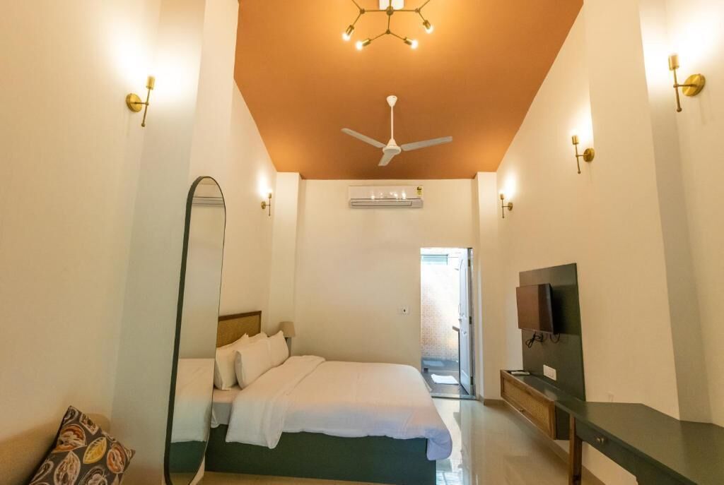Un dormitorio con cama, ventilador de techo, televisor y un espejo grande.