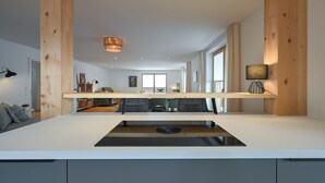 A modern kitchen with a central island, wooden beams, and a view into the dining area. - New & high-quality furnished guest house in a quiet location - Burgberg im Allgäu (Burgberg im Allgäu)