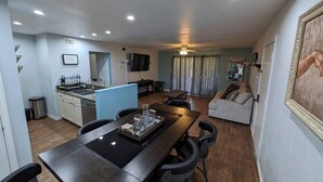 Un espace de vie compact comprenant un coin repas, une kitchenette et un salon.