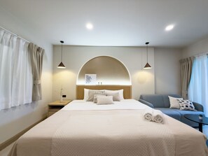 Une chambre d’hôtel moderne avec un grand lit, un canapé, une petite table et une œuvre d’art accrochée au mur.