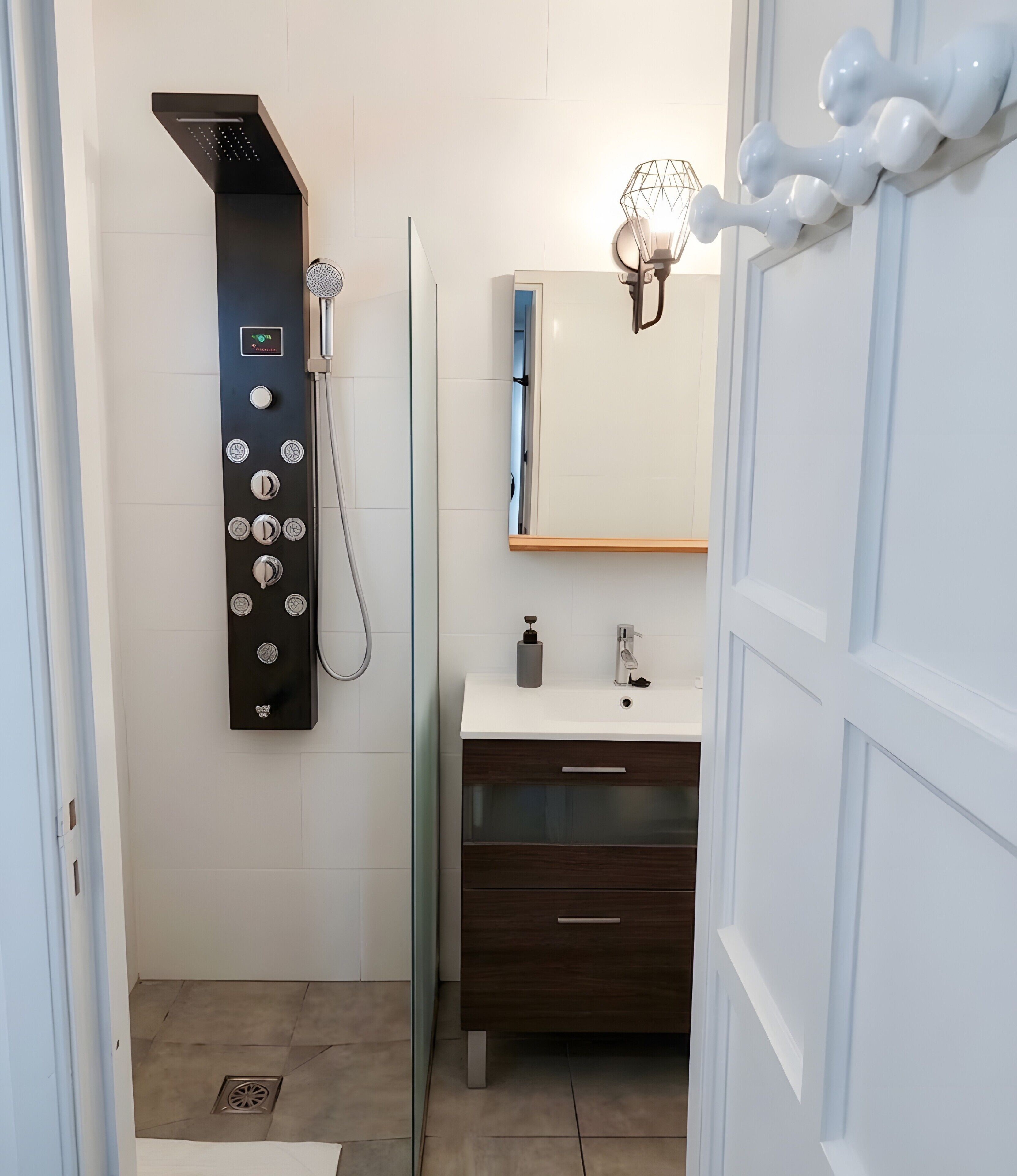 Een badkamer met een douche, wastafel, spiegel en handdoekhouder.