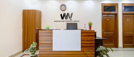 A reception desk with a logo, a plant, and a wooden cabinet.