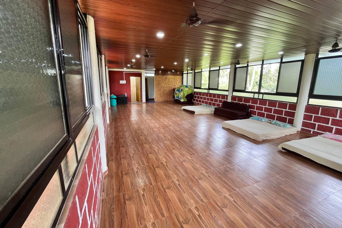 A spacious room with a wooden floor, a red brick wall, and a large window.