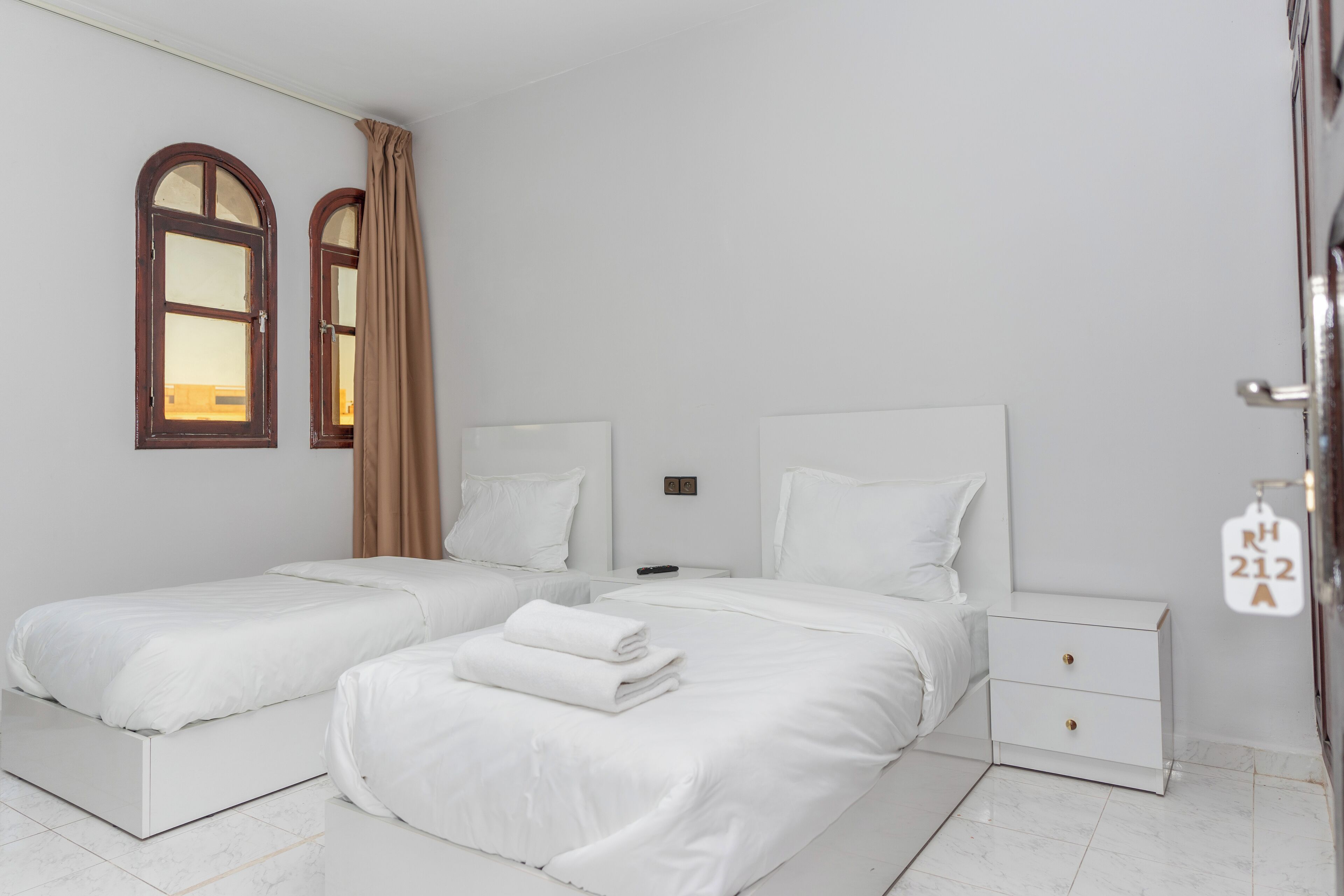 Une chambre moderne avec deux lits simples, une table de chevet et une armoire.