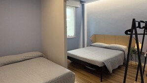 A compact room with two beds, a wooden floor, and a small table with a plant. - Apartment in the center of Igea Marina (Bellaria-Igea Marina)