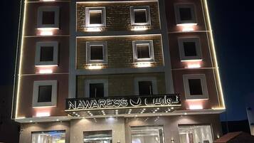 A multi-story hotel with illuminated windows and a sign reading 'NAWARESS J. LALANI'.