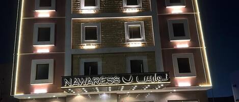 A multi-story hotel with illuminated windows and a sign reading 'NAWARESS J. LALANI'.