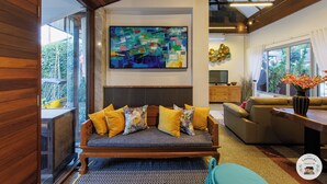 Un salon moderne avec un grand tableau abstrait, un plafond en bois et une vue sur la verdure à l’extérieur.