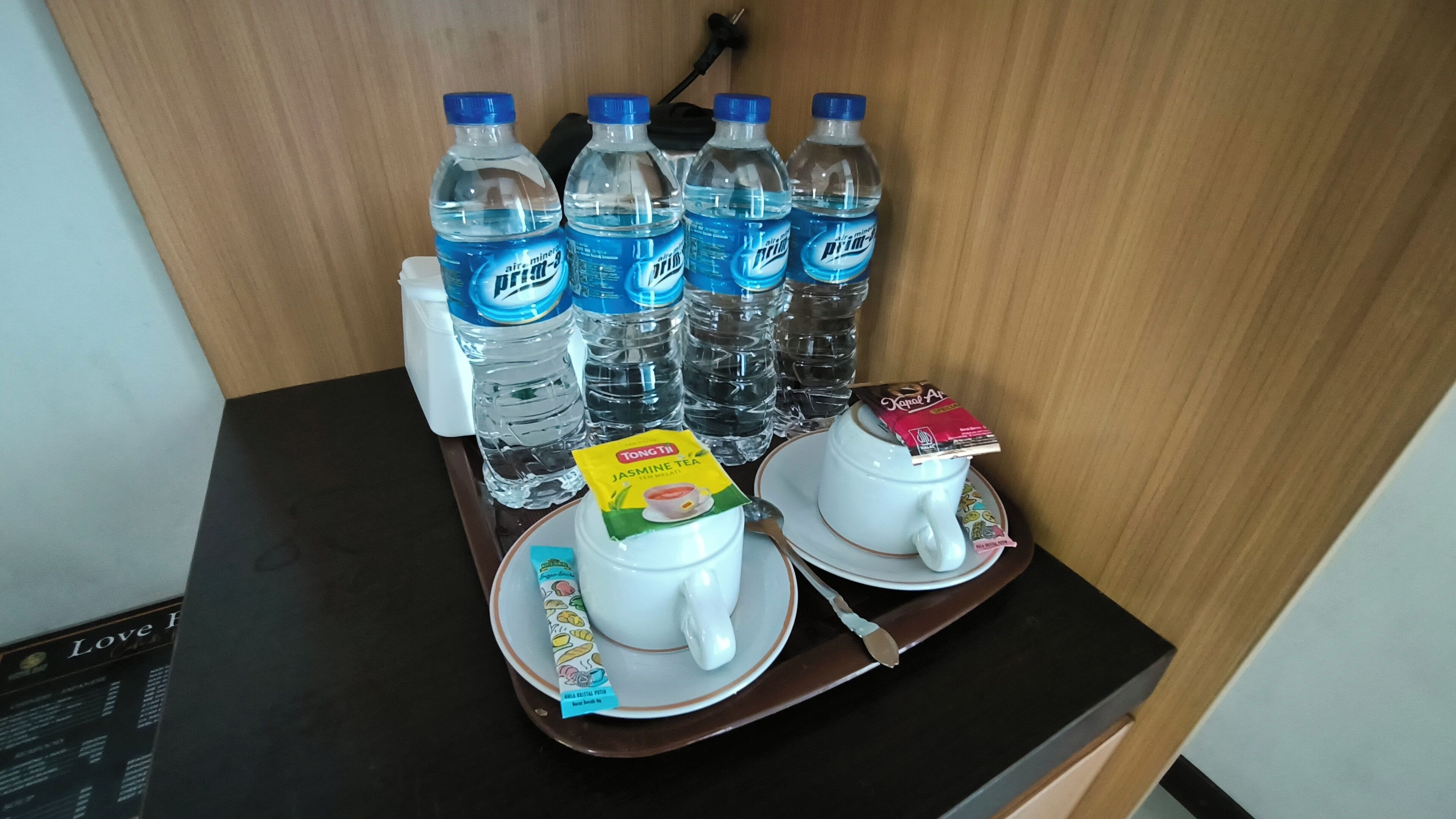 A tray with water bottles, a teapot, a teacup, and a packet of jasmine tea.