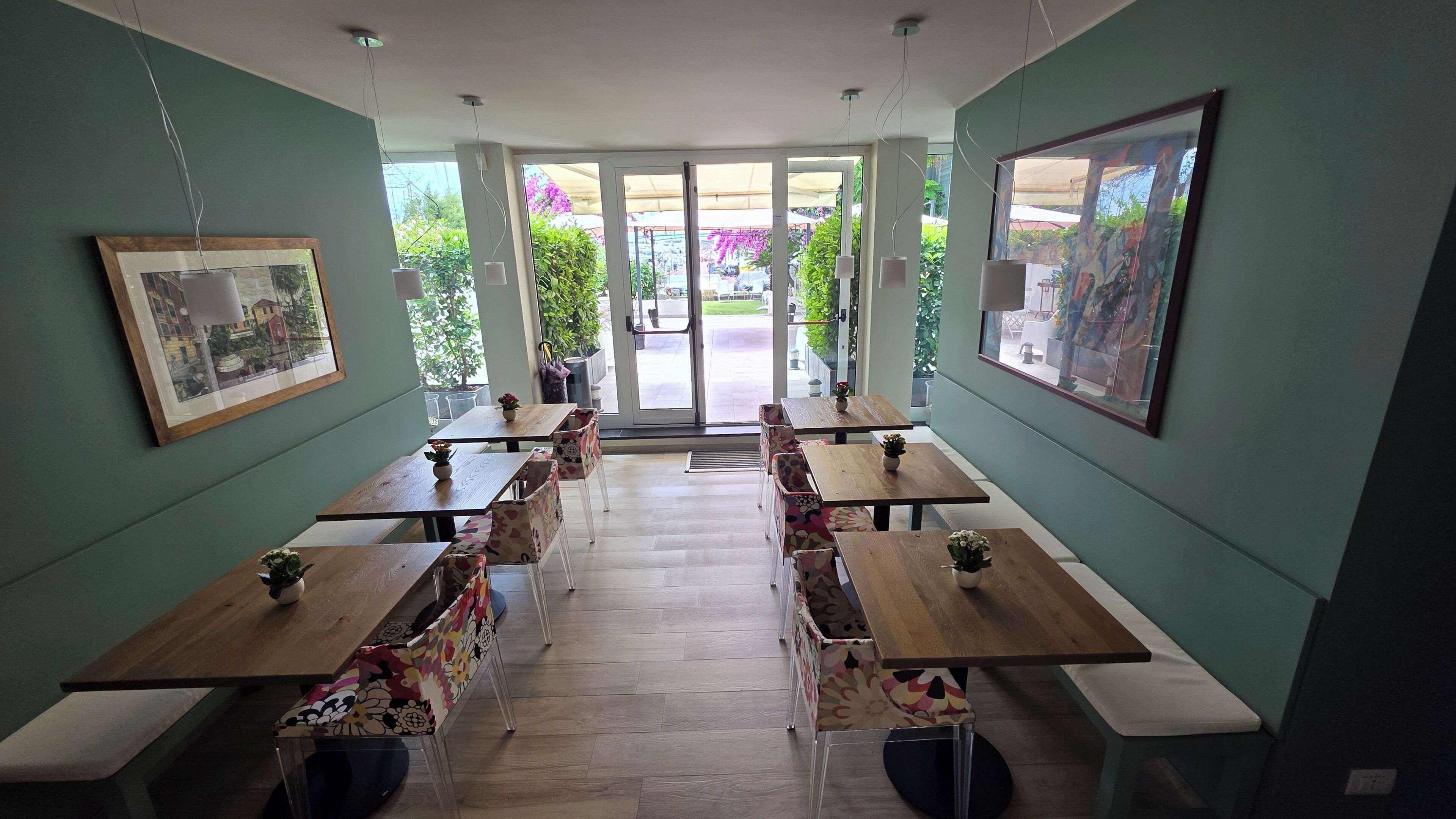 A restaurant with a central open area, wooden tables, and chairs, and framed artwork on the walls.