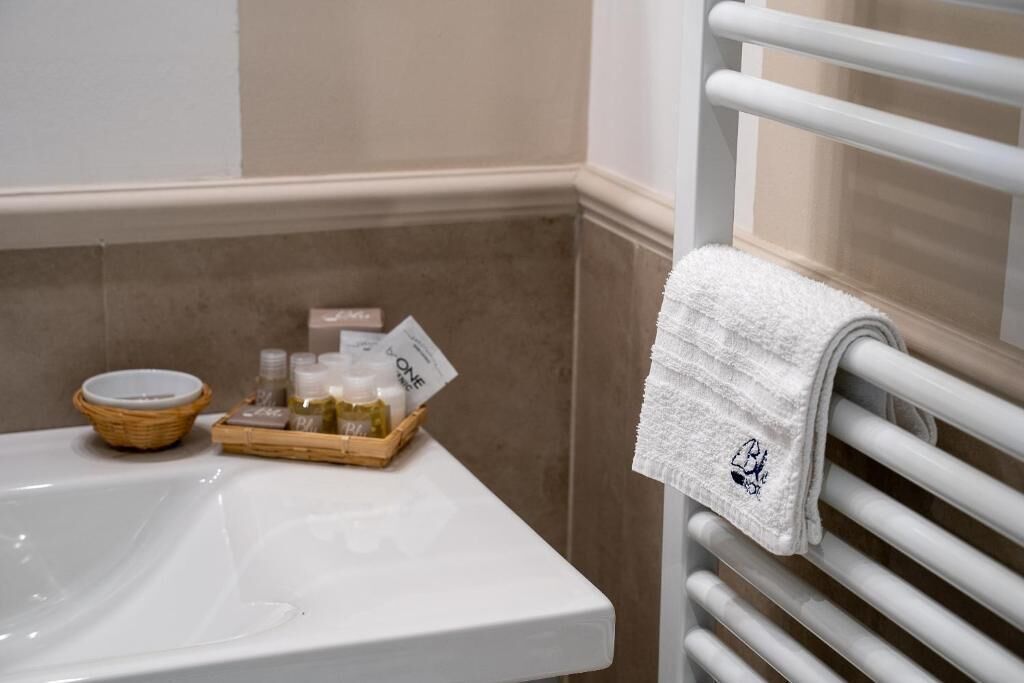 A bathroom with a white sink, a towel rack, and a tray with toiletries.
