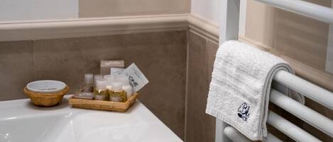 A bathroom with a white sink, a towel rack, and a tray with toiletries.