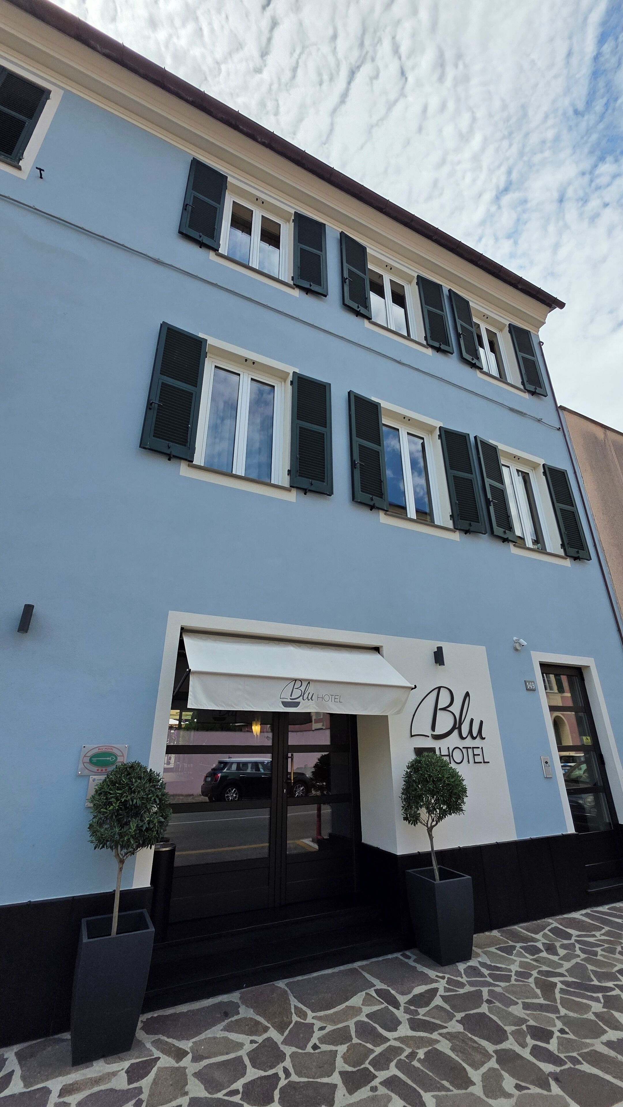 Ein zweistöckiges Hotel mit einem Schild, auf dem „Blu Hotel“ steht.
