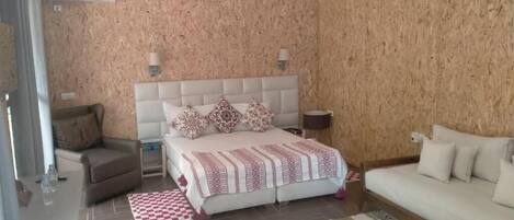 Un dormitorio con una cama grande, dos lámparas de noche, un sofá y una alfombra estampada.