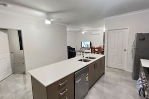 A modern kitchen with a central island, built-in dishwasher, and a dining area with a TV. - 2 House Together 7 BR Ideal for Large Families (Hillcrest)