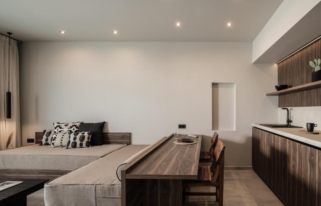 Um espaço de estar moderno e minimalista com uma mesa de jantar de madeira, um sofá com almofadas estampadas e uma cozinha planejada com armários de madeira.