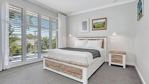 Un dormitorio con cama, mesita de noche y ventana con persianas.