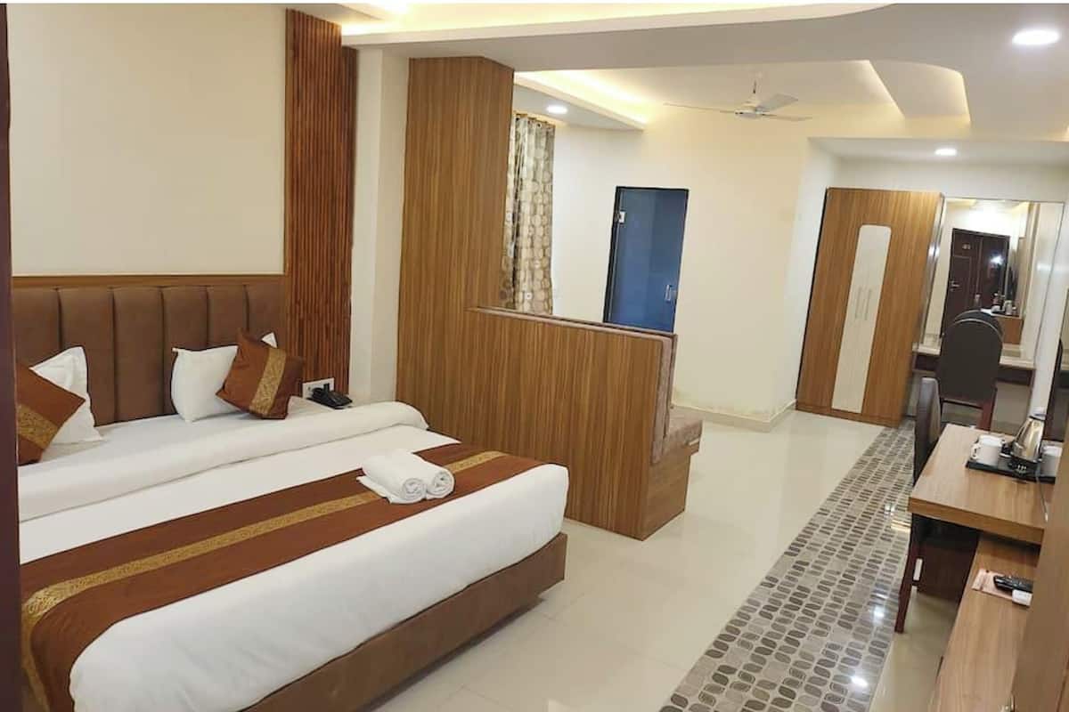 A hotel room with a large bed, a desk, and a mirror.