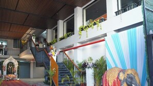 A staircase with a red carpet leading to a balcony, decorated with plants and flowers. - Hotel Bajaj Residency (Nanded)