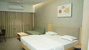 Ein Hotelzimmer mit Bett, Stuhl, Nachttisch und Wandklimaanlage.