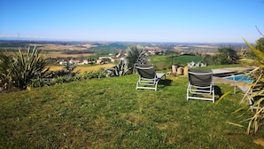 Una zona verda amb dues cadires orientades a una vista panoràmica d'una vall i muntanyes llunyanes.
