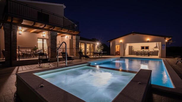 Un área de piscina moderna al aire libre con un jacuzzi, una zona de estar techada y un espacio para comer.