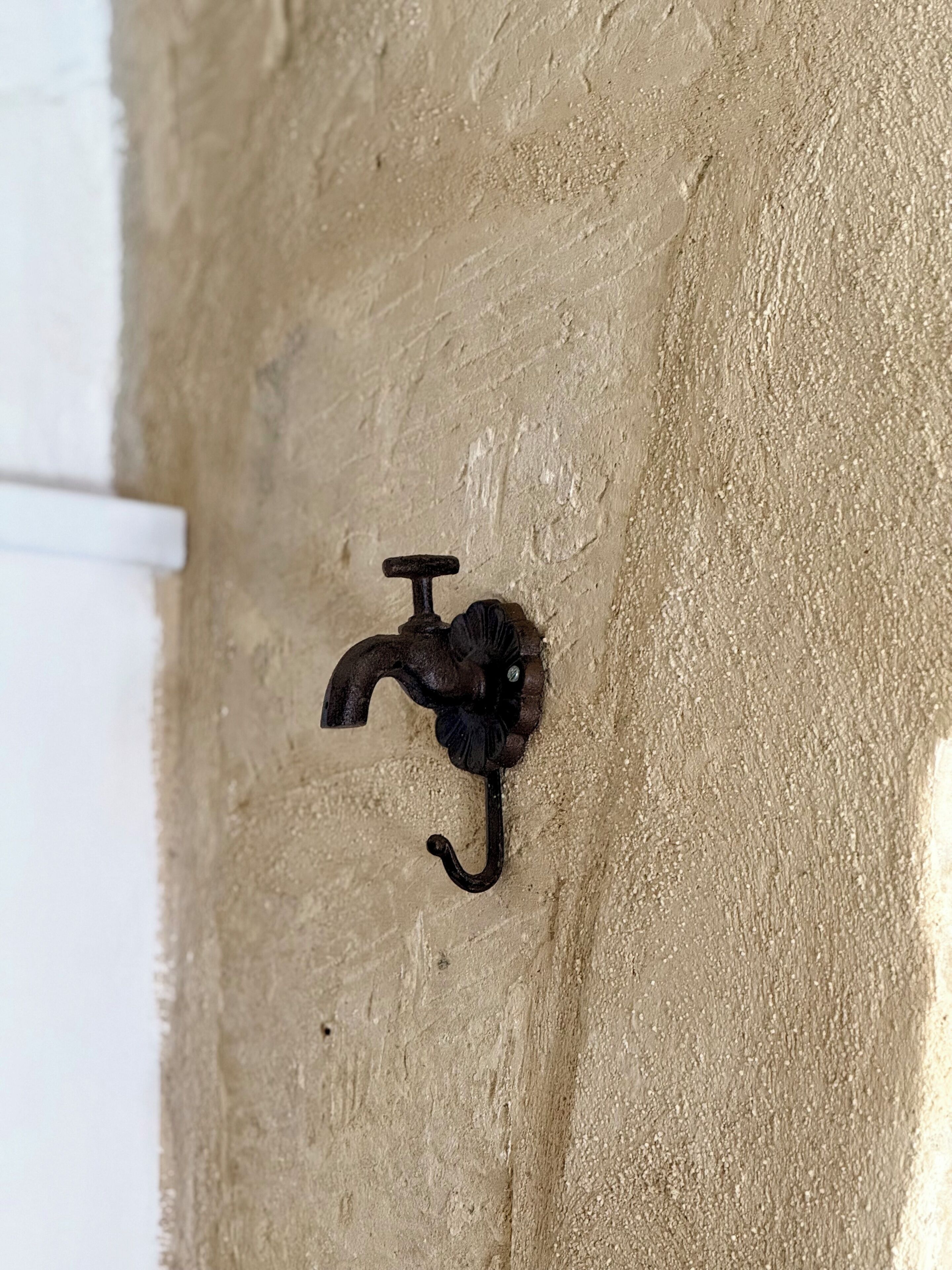 Un primer plano de un grifo metálico montado en la pared, con caño curvo y un mando de palanca.