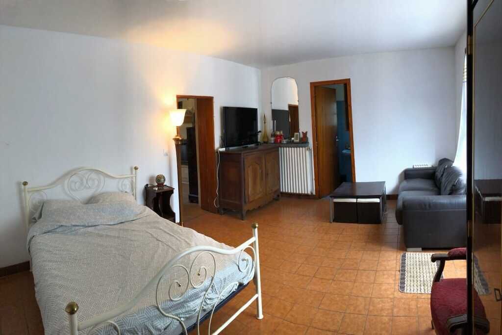 Een slaapkamer met een bed, een bureau, een televisie en een bank.