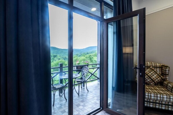 Una stanza con una porta scorrevole in vetro che dà su un balcone esterno con tavolo e sedie.