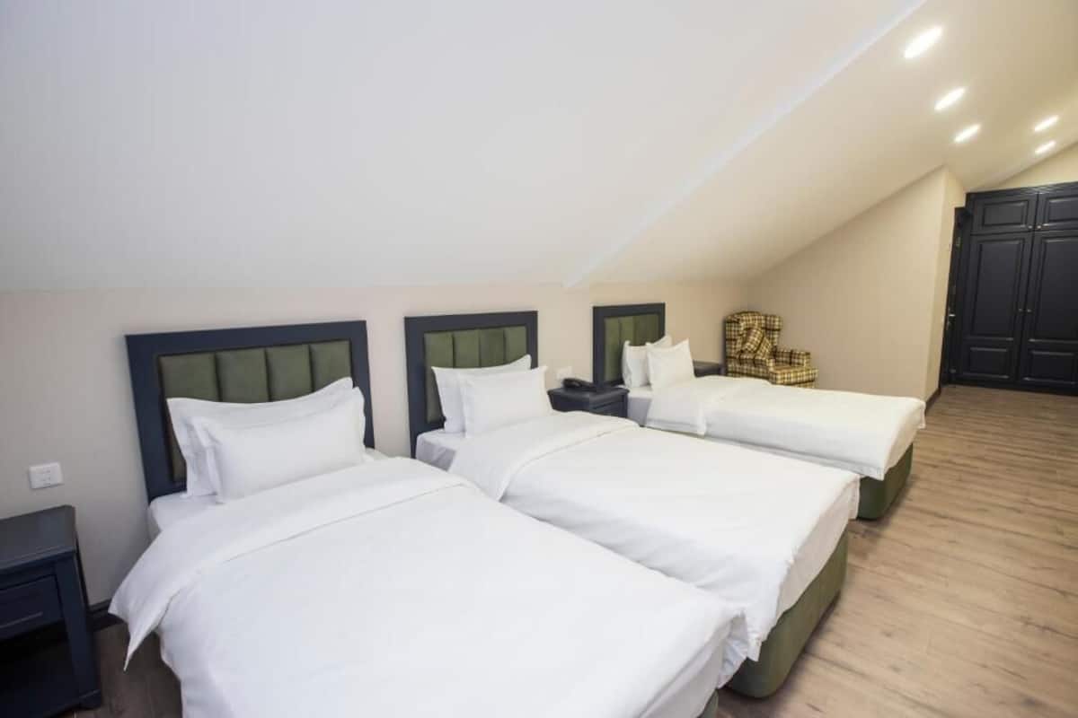 A hotel room with three beds, a chair, and a wardrobe.