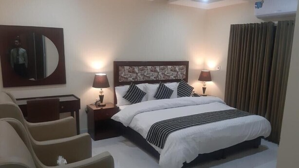 Habitación de hotel con una cama grande, dos lámparas de noche, un escritorio y una silla.