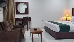 Una habitación de hotel con cama, escritorio, silla y una mesita.