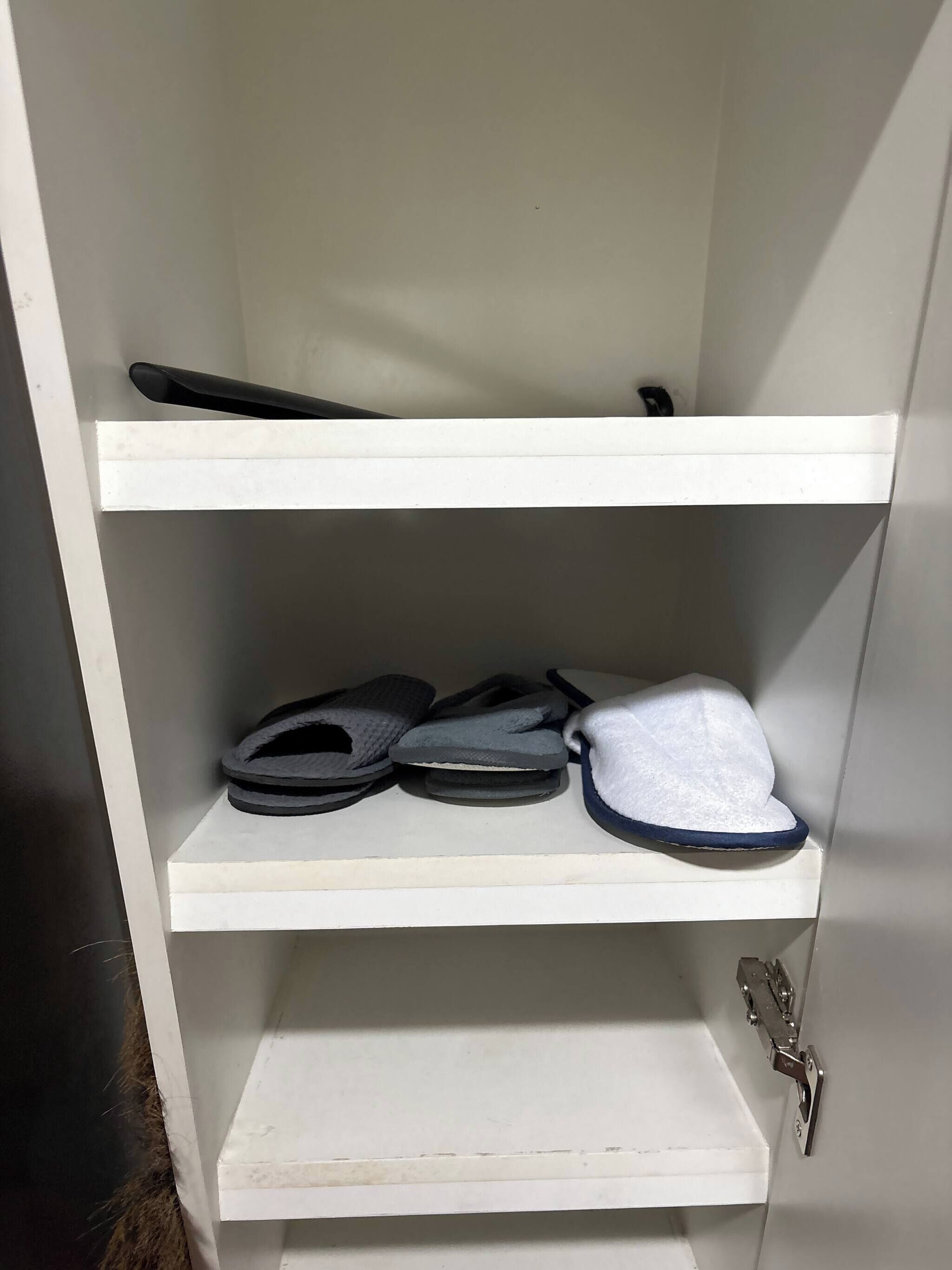 A white shelf unit with three shelves, each holding different items.