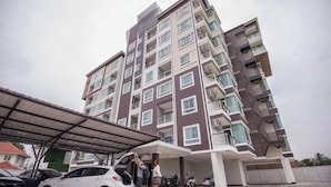 A multi-story residential building with balconies, a covered parking area, and a car parked in front. - Quiet Condo, Minutes to Everything (Chiang Mai)