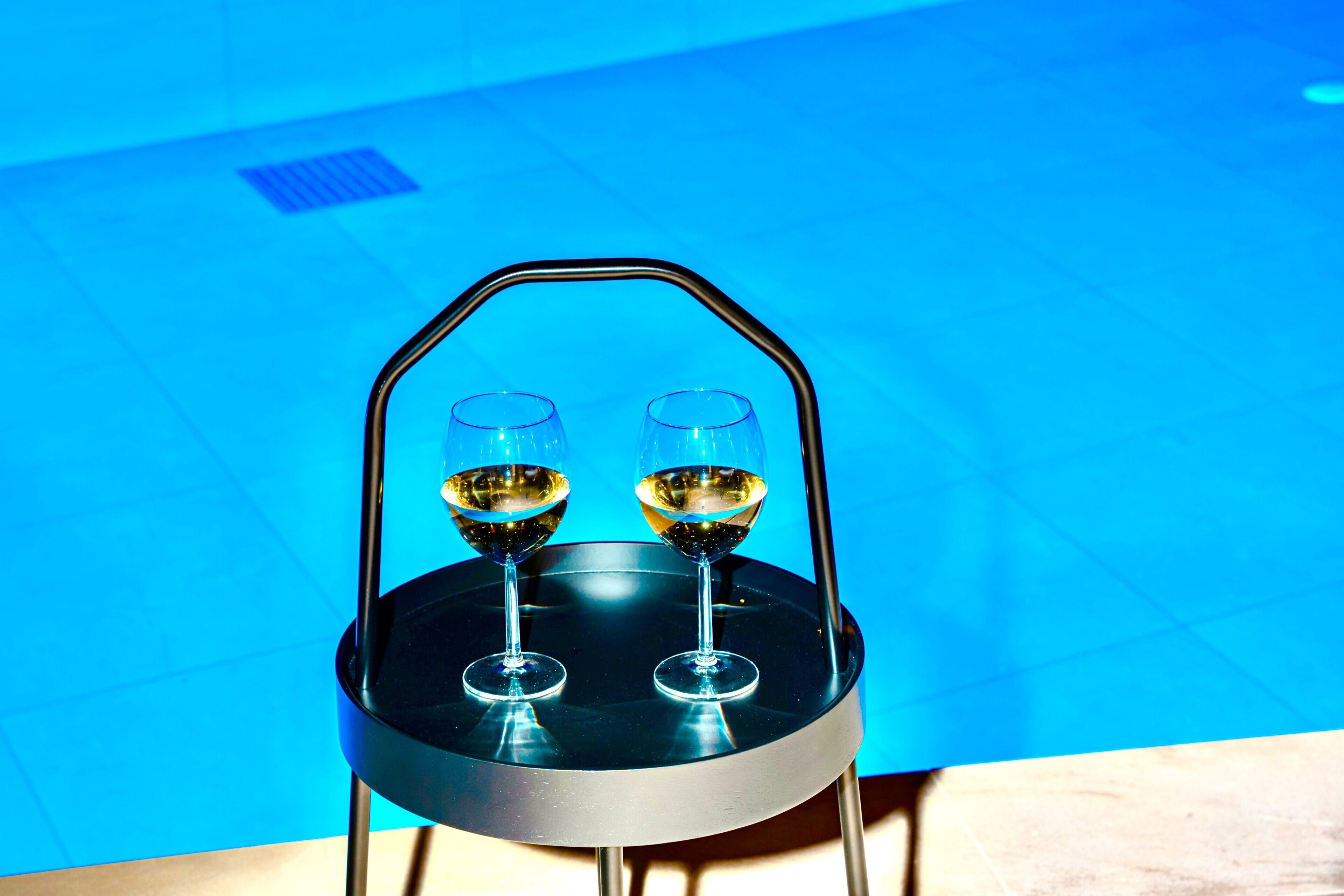 A round table with a black metal frame and two wine glasses on it.