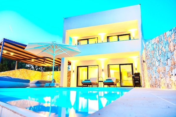 A modern two-story building with a swimming pool, outdoor seating, and stone walls. - Luxurious 6 persons Villa 'Selene 3' with private pool & mountain and countryside views (Rhodes)
