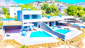 A modern villa with two swimming pools, a covered patio, and a view of the surrounding landscape. - Luxurious 6 persons Villa 'Selene 3' with private pool & mountain and countryside views (Rhodes)