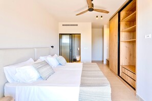 A bedroom with a bed, a ceiling fan, a wooden wardrobe, and a hallway leading to a door. - Luxurious 6 persons Villa 'Selene 3' with private pool & mountain and countryside views (Rhodes)