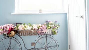 Een kamer met een raam, een fiets met een bloemenmand, en een gestreept tapijt.