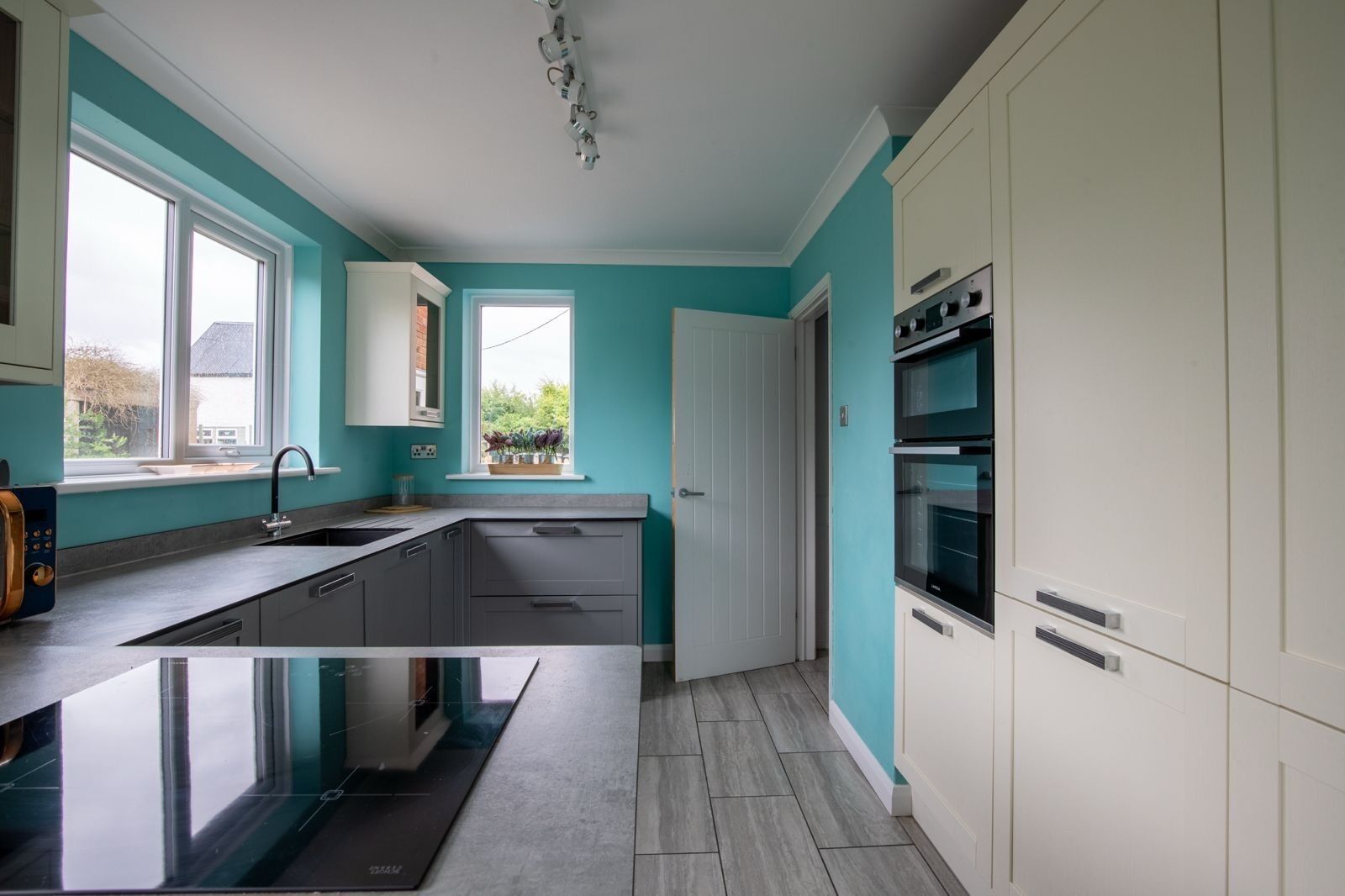 Een moderne keuken met een centraal eiland, witte kasten en een raam voor natuurlijk licht.