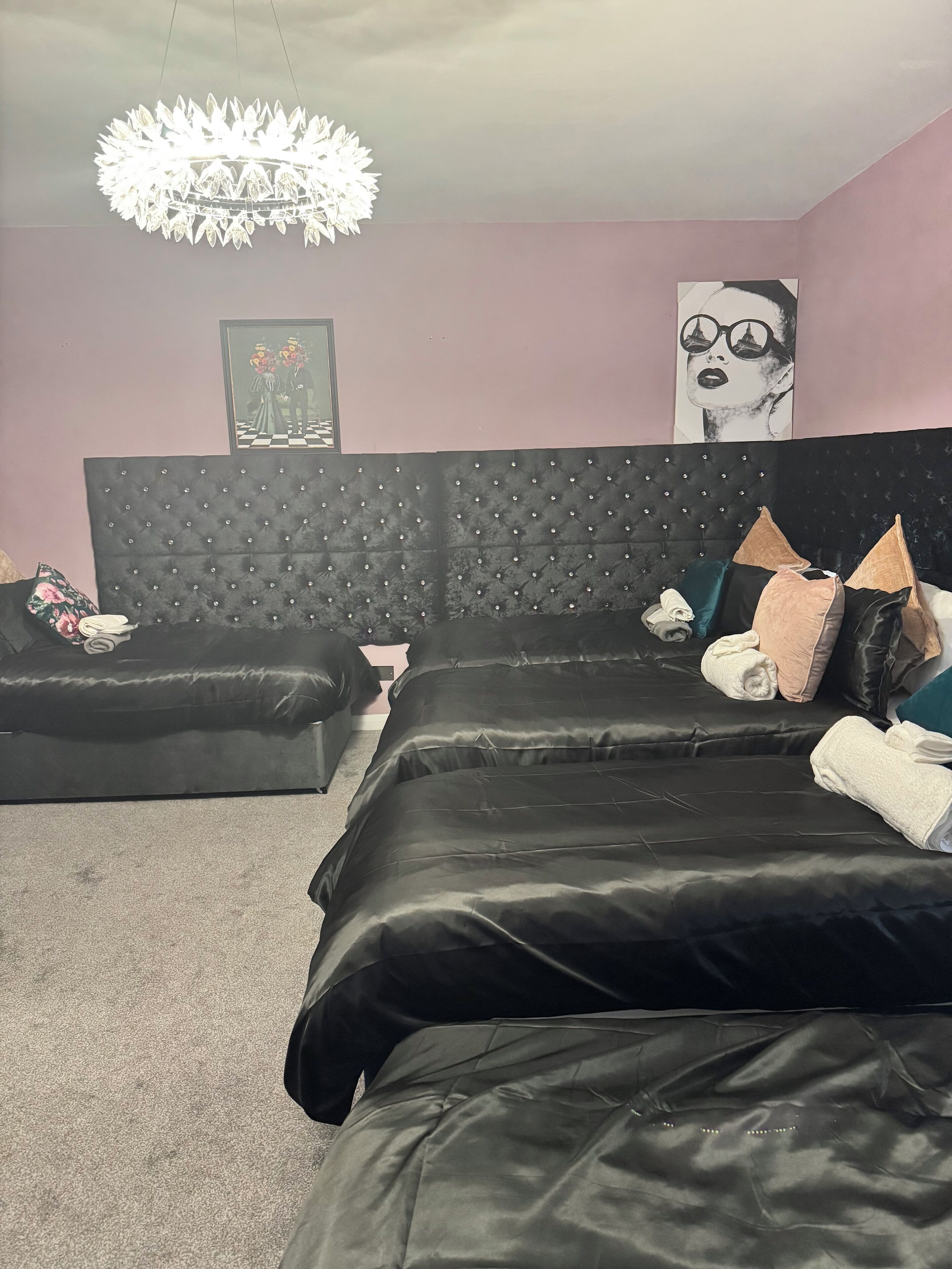 A bedroom with a tufted headboard, a black sofa, and a bed with pillows and towels.